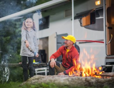 Father with Daughter in Front of Campfire Having Fun at RV Park.