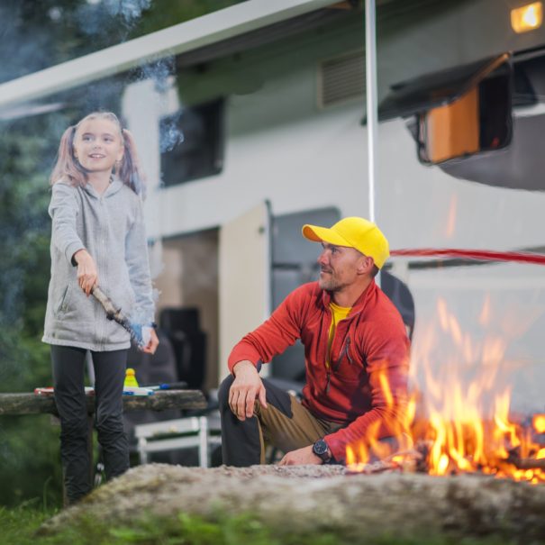 Father with Daughter in Front of Campfire Having Fun at RV Park.