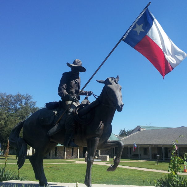 Metal statue of ranger holding the Texas flag outside Texas Ranger Hall of Fame and Museum