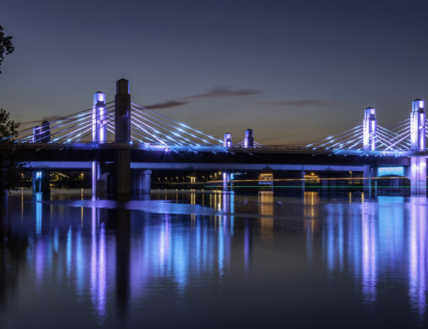 bridge with purple and blue lights across river